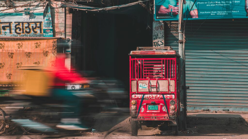 Motion blur of a scooter speeding past a vibrant street scene in Patna, India.